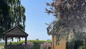 A gazebo in a garden with potted plants and a building in the background.
