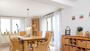 A dining area with a wooden table and wicker chairs, a wooden cabinet, and a wicker storage unit with baskets.