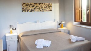 Een slaapkamer met een bed, nachtkastjes, een lamp en een raam.