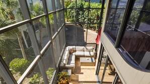 Ein moderner Balkon mit Glaswänden, einer gepolsterten Sitzecke und einem Blumentopf.