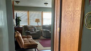Ein Flur, der in ein Wohnzimmer mit einer Couch, einem Teppich und einer Wanduhr führt.