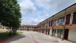 Un motel con varias habitaciones, un estacionamiento y un árbol.