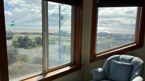 A room with a view of an airport, a chair, and a window sill.