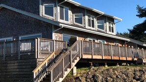 A two-story house with a wooden deck and a stone foundation.