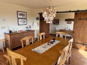 A dining area with a wooden table, chairs, a chandelier, and a wooden cabinet. - LAST MIN JULY OPENINGS! Beach house getaway (Pacific Beach)