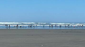 A wide beach with people walking along the shore.