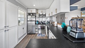A modern kitchen with white cabinets, stainless steel appliances, and a black countertop. - Beach/Bay, Boat/Fish, Sand/Surf, Deck/Vistas (Freeport)
