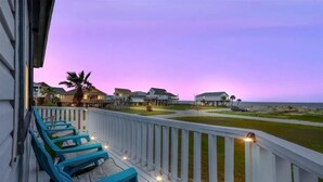 A balcony with blue chairs and string lights, overlooking a beach and houses. - Beach/Bay, Boat/Fish, Sand/Surf, Deck/Vistas (Freeport)