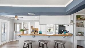A kitchen with a wooden bar counter, three stools, and various kitchen appliances. - Beach/Bay, Boat/Fish, Sand/Surf, Deck/Vistas (Freeport)