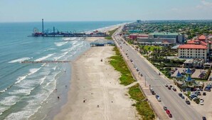A coastal cityscape with a beach, a pier, and a road lined with buildings. - Beach/Bay, Boat/Fish, Sand/Surf, Deck/Vistas (Freeport)