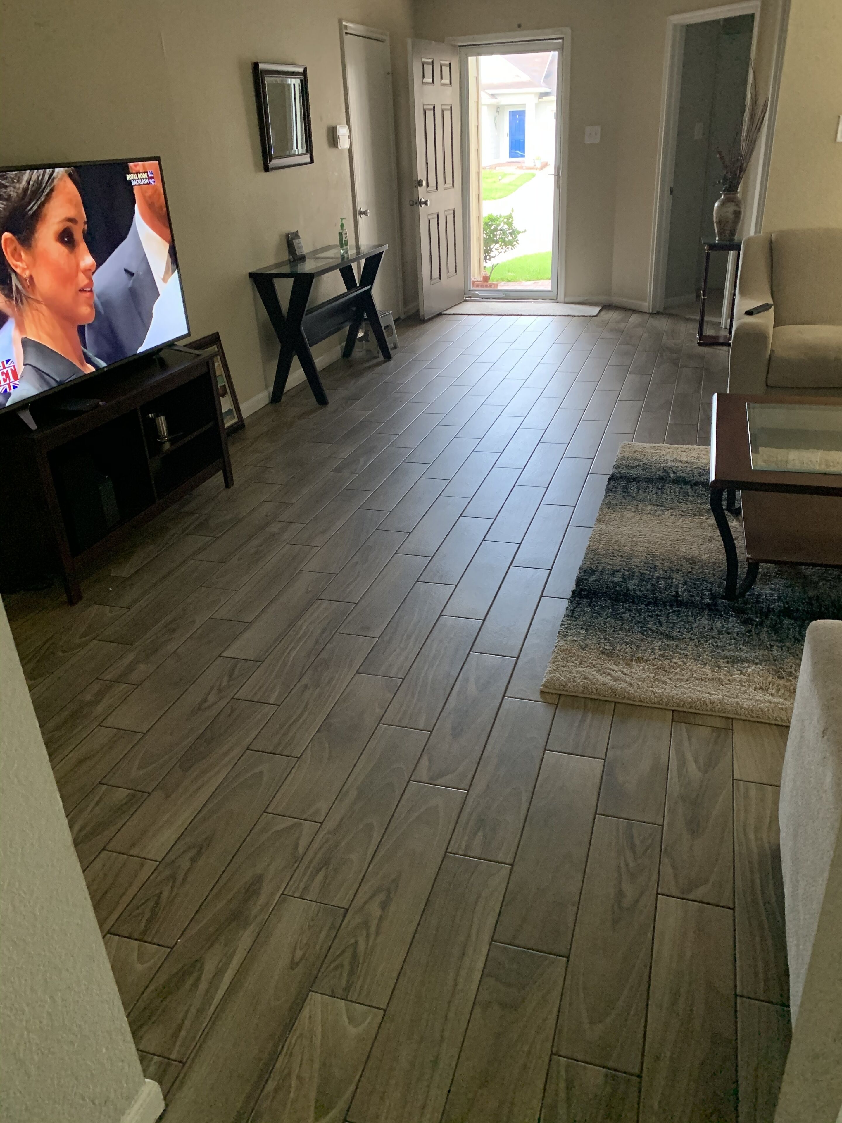 Ein Wohnzimmer mit Fernseher, einer Couch, einem Couchtisch und einer Tür, die nach draußen führt.