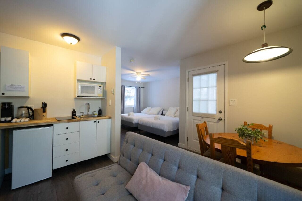 Un espace de vie compact comprenant un coin cuisine, un canapé, une table à manger et une petite chambre.
