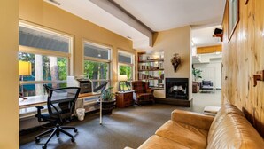 Una sala de estar acogedora con un sofá de cuero, un escritorio con una computadora, una chimenea y una estantería.