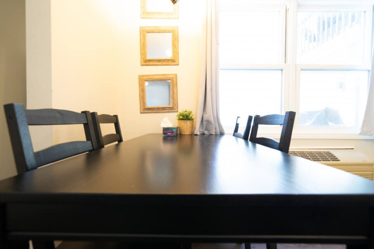 A dining table with four chairs, a small potted plant, and three framed pictures on the wall.