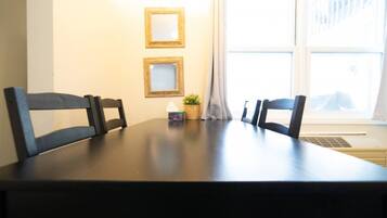 A dining table with four chairs, a small potted plant, and three framed pictures on the wall.