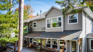 Une maison à deux étages dotée d’un patio couvert, d’un espace salon extérieur et d’une petite terrasse.