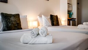 Une chambre d’hôtel avec deux lits, chacun agrémenté de draps blancs et de serviettes pliées. Il y a des oreillers sur les lits, ainsi qu’une table de chevet avec une lampe.