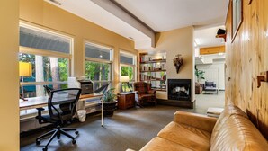 A spacious living room with a leather couch, a desk with a computer, and a fireplace.