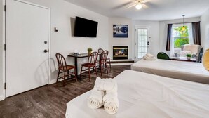 Une chambre d’hôtel avec deux lits, une télévision, une cheminée et un coin repas avec des chaises.