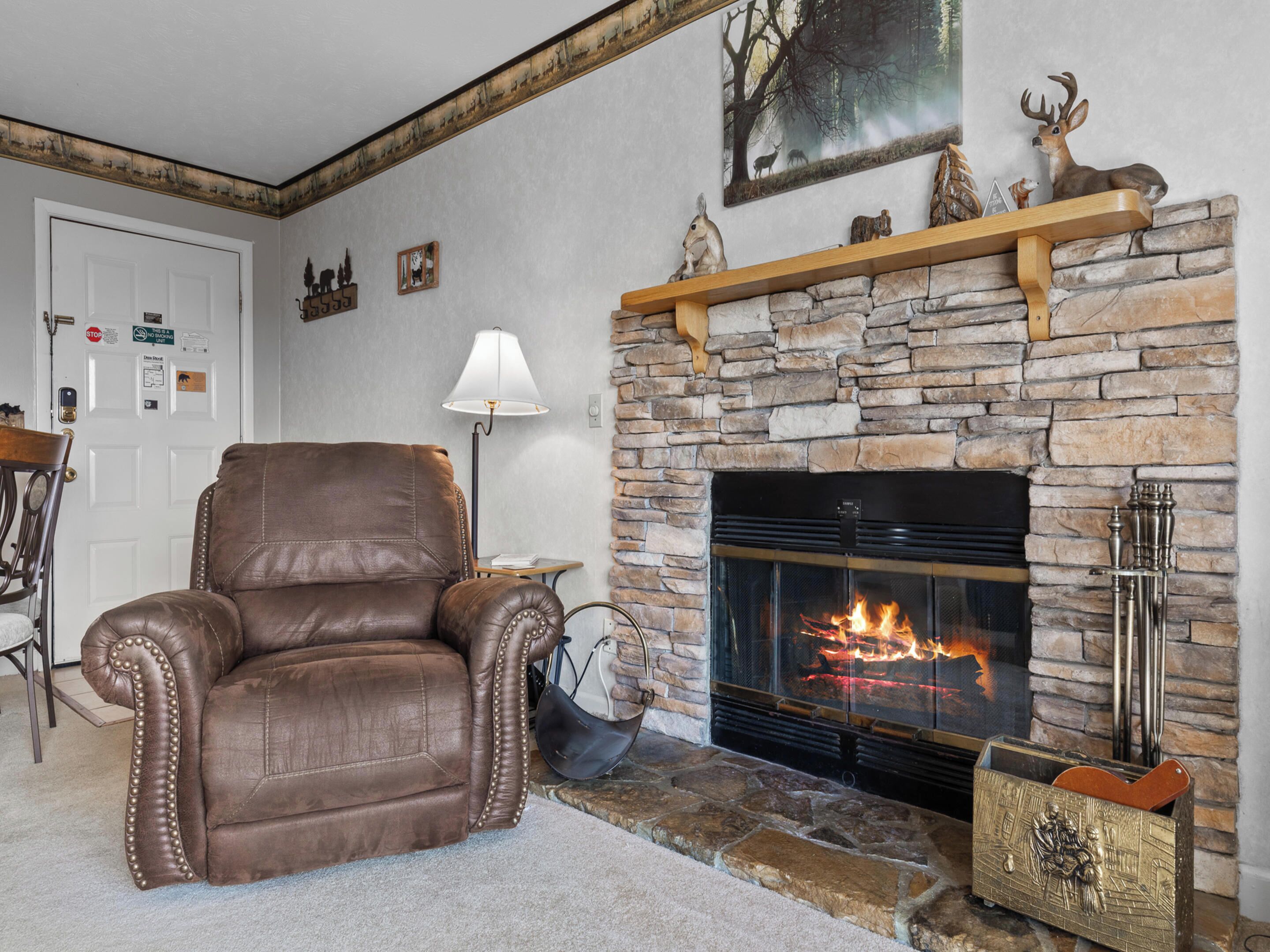 A cozy living room with a stone fireplace, leather armchair, and a mounted deer head.