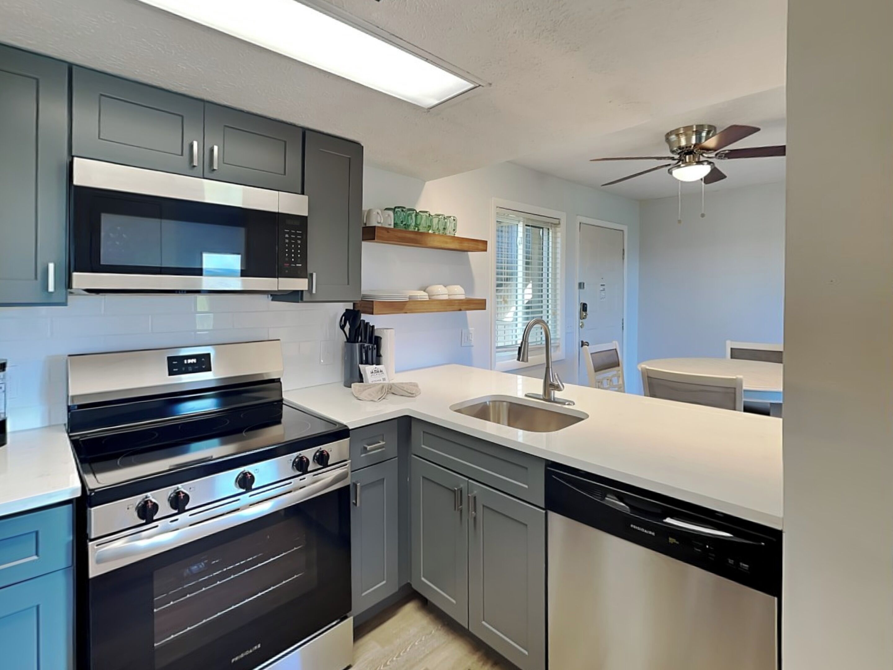 A modern kitchen with grey cabinets, a stainless steel range, a microwave, and a dishwasher.