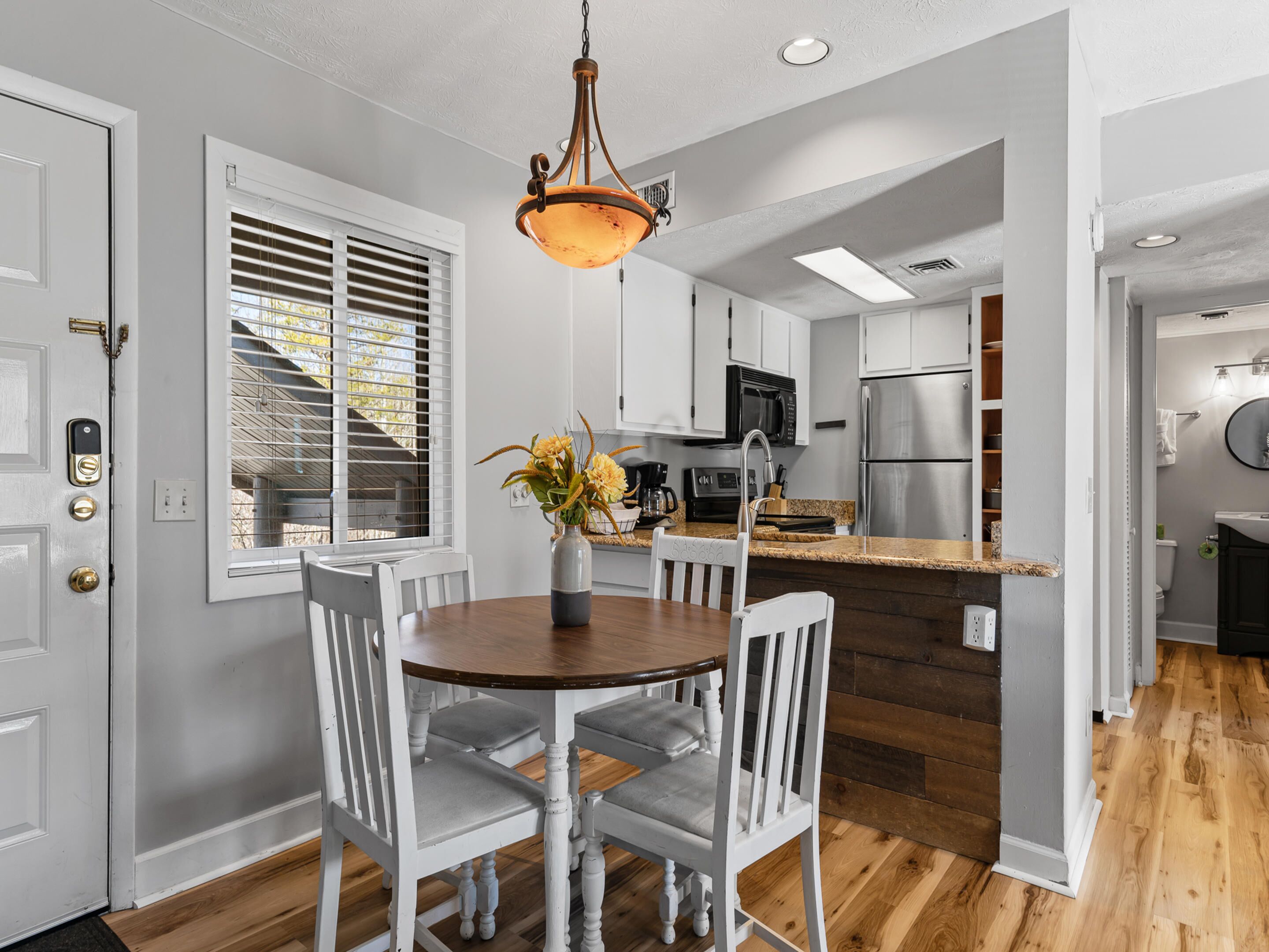 A modern kitchen with white cabinetry, a stainless steel refrigerator, and a wooden island.