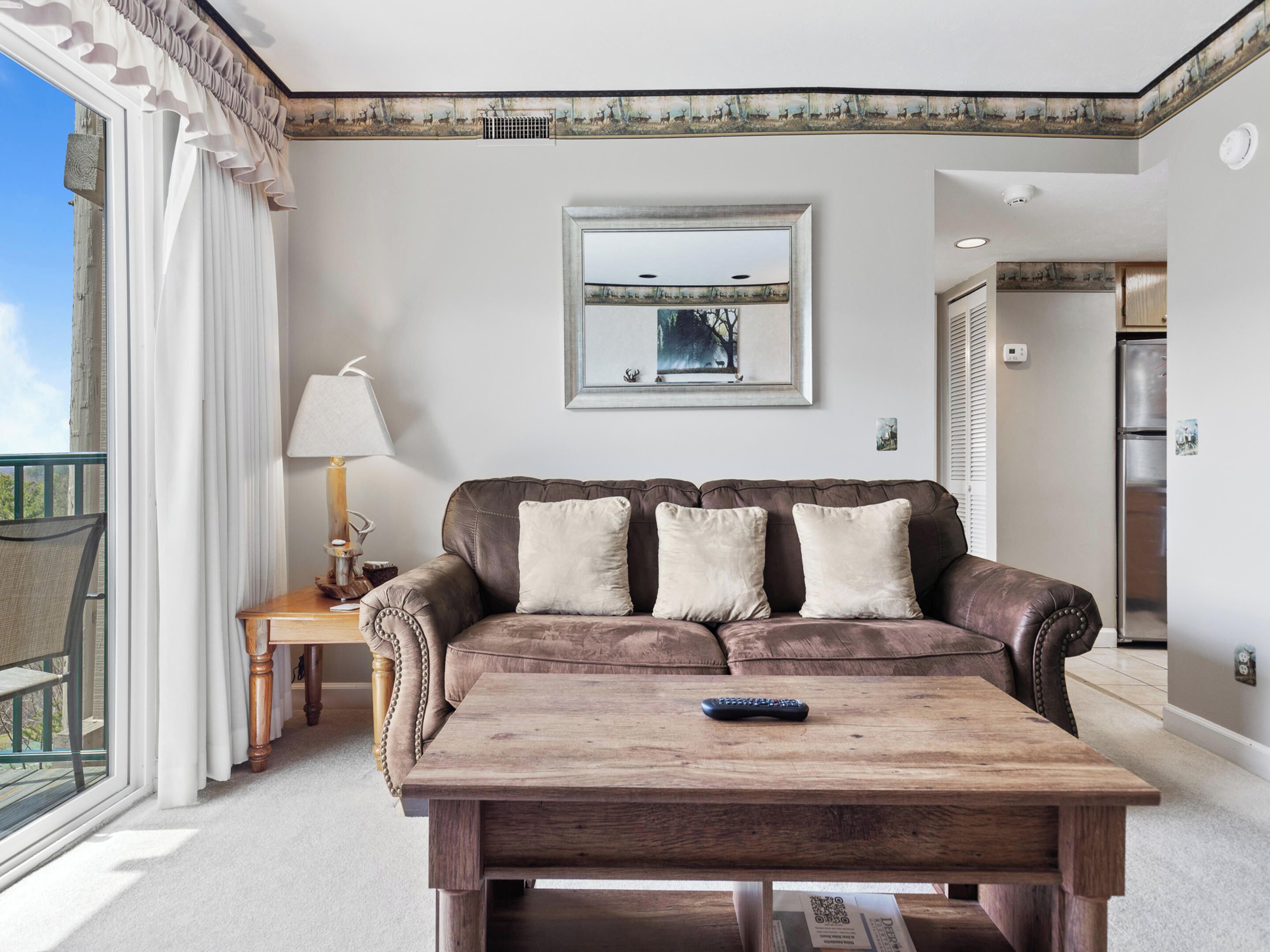 A living room with a brown leather sofa, a wooden coffee table, and a framed picture on the wall.