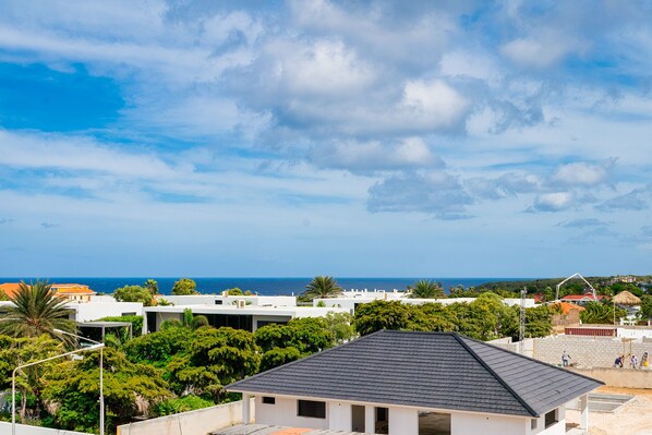 A coastal residential area with modern houses, a clear sky, and the ocean in the background.