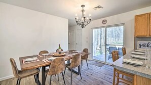 A dining area with a wooden table set for six, surrounded by upholstered chairs. A chandelier hangs from the ceiling, and a wooden cabinet is visible to the right. - Villa in Arrowhead Pocono Resort community Walking to the Lake  . (Pocono Lake)