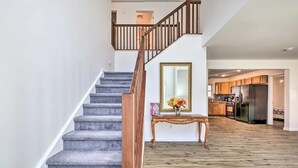 A staircase with wooden railings leading to a second floor, a console table with a vase of flowers, and a kitchen area with wooden cabinets and a stainless steel refrigerator. - Villa in Arrowhead Pocono Resort community Walking to the Lake  . (Pocono Lake)