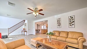 A spacious living room with a large tan leather sofa, a wooden coffee table, and a ceiling fan. A staircase leads to an upper level. - Villa in Arrowhead Pocono Resort community Walking to the Lake  . (Pocono Lake)