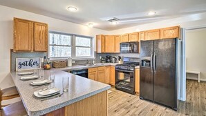 A modern kitchen with wooden cabinets, a granite countertop, stainless steel appliances, and a window providing natural light. - Villa in Arrowhead Pocono Resort community Walking to the Lake  . (Pocono Lake)