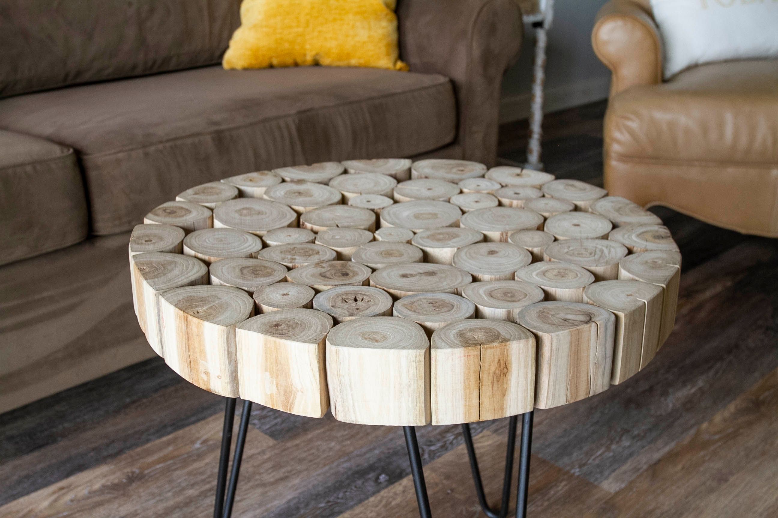 Ein runder Couchtisch aus Holz mit natürlicher Holzoptik, schwarzen Metallbeinen und einem kreisförmigen Design.