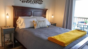 A neatly made bed with a gray and white striped bedspread, a yellow throw blanket, and two bedside lamps on matching nightstands. - Modern treehouse in the woods near SDC! (Reeds Spring)