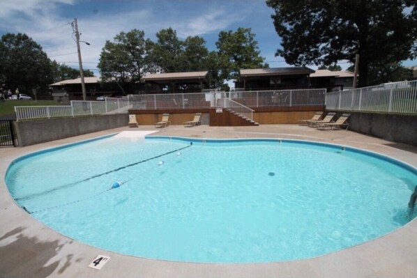 Guests can enjoy a refreshing swim in the pool surrounded by a grassy lawn and trees.