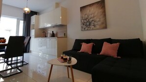 Ein modernes Wohnzimmer mit einer schwarzen Couch, einem Couchtisch und einem Essbereich mit einem Stuhl und einem Tisch.