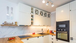 Eine moderne Küche mit weißen Schränken, einer Holz Arbeitsplatte und einem schwarzen Backofen.