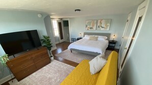 Une chambre à coucher avec un lit, une télévision, une commode et une plante.