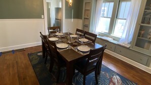 Une salle à manger avec une table en bois dressée pour six personnes, entourée de chaises.