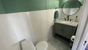 A bathroom with a white toilet, a sink with a mirror above it, and a towel hanging on the wall.