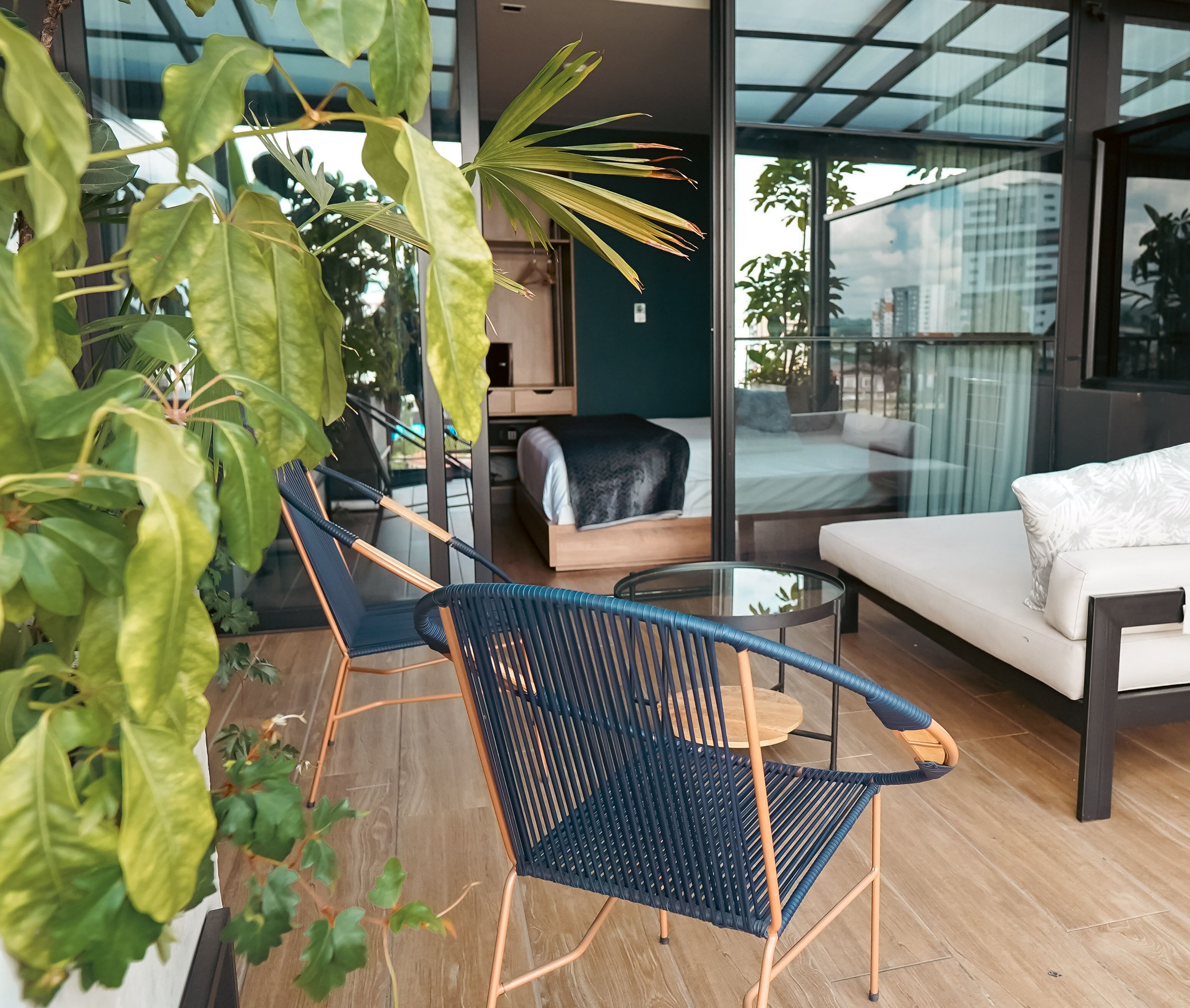 Ein modernes Wohnzimmer mit Glaswand, einer Couch, einem Couchtisch und zwei Sesseln.