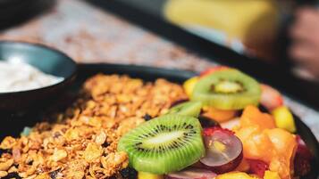 A plate of granola with various fruits and a small bowl of yogurt.