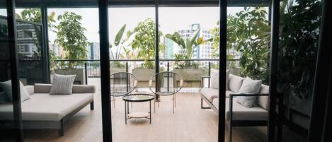 A modern living room with a glass door leading to a balcony, furnished with a sofa, chairs, and a coffee table.