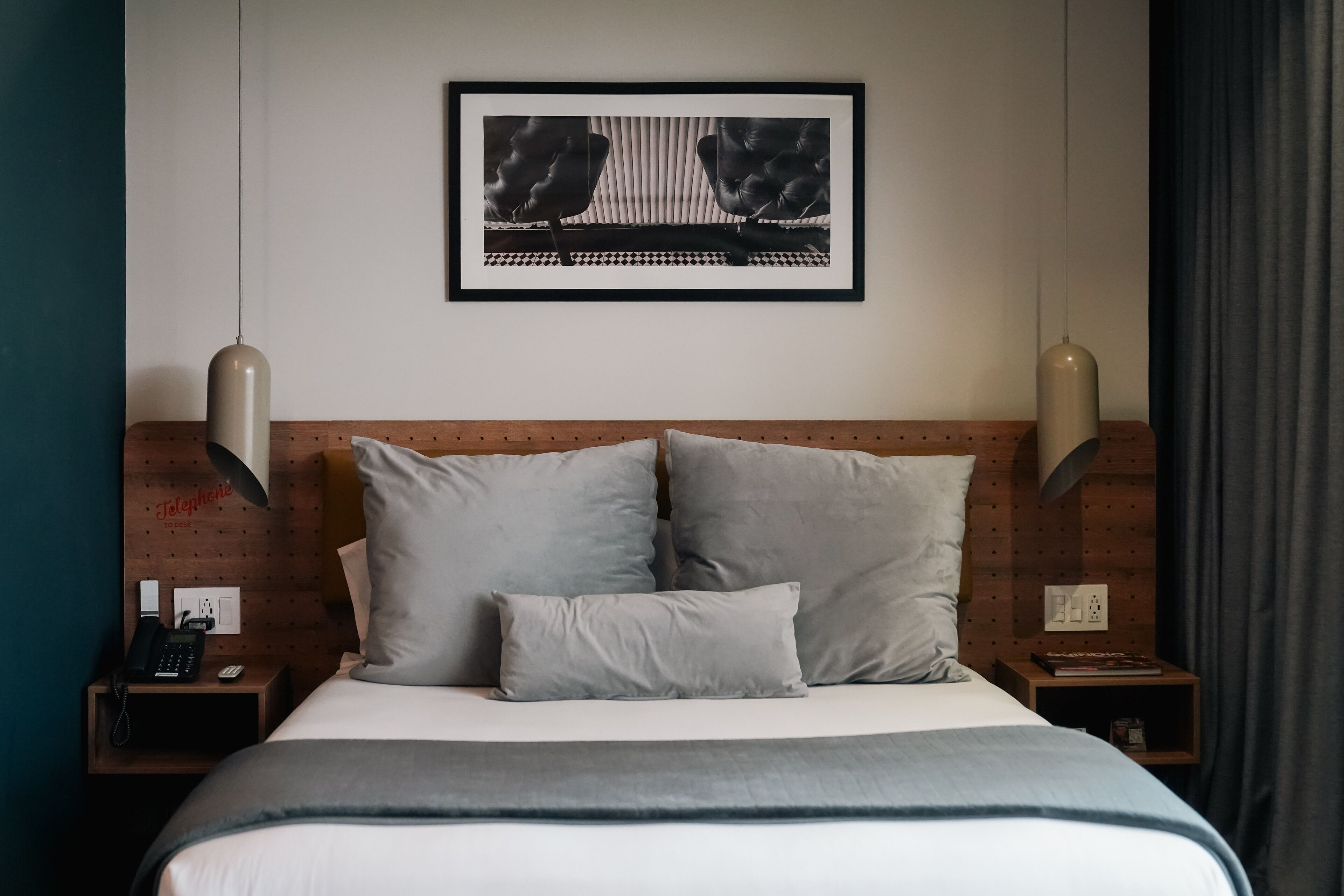 A neatly arranged hotel room with a large bed, two bedside tables, a telephone, and a framed artwork above the bed.