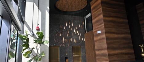 Un moderno vestíbulo con una planta grande, un mostrador de recepción de madera e iluminación colgante en el techo.