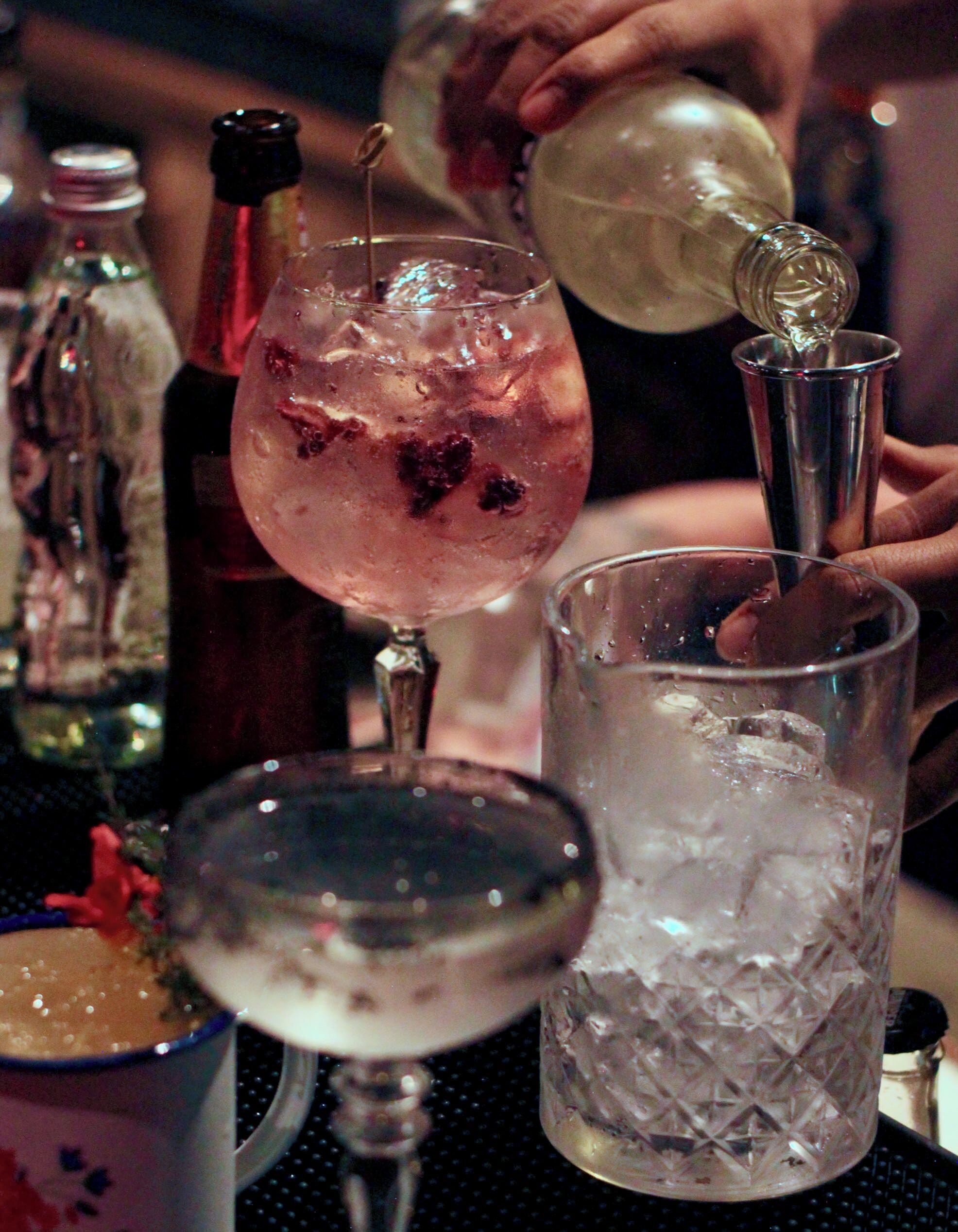 A bar setting with various glasses and bottles, including a cocktail with a garnish and a bottle with a cork.