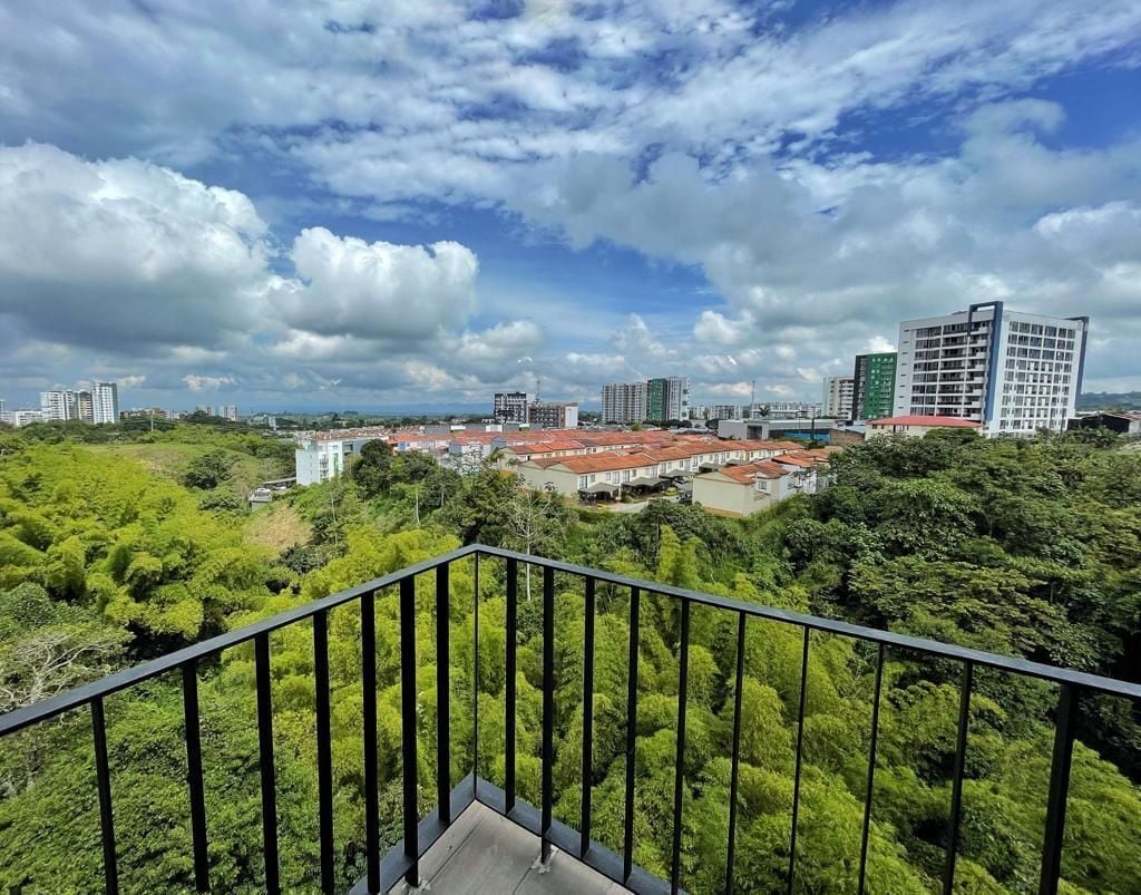 A balcony with a view of a cityscape, including buildings and greenery.