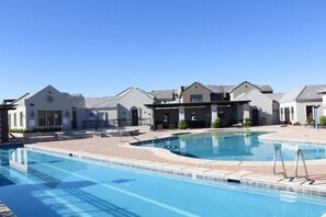 Relax by the pool surrounded by a paved walkway and adjacent to a building with a flat roof and windows.