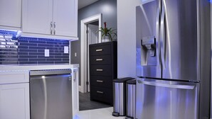 Une cuisine moderne équipée d’appareils électroménagers en acier inoxydable, d’un lave-vaisselle et d’un meuble noir avec des tiroirs.