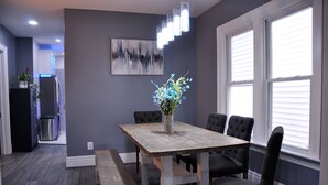 Un coin repas avec une table en bois, des chaises à revêtement noir et un vase rempli de fleurs.